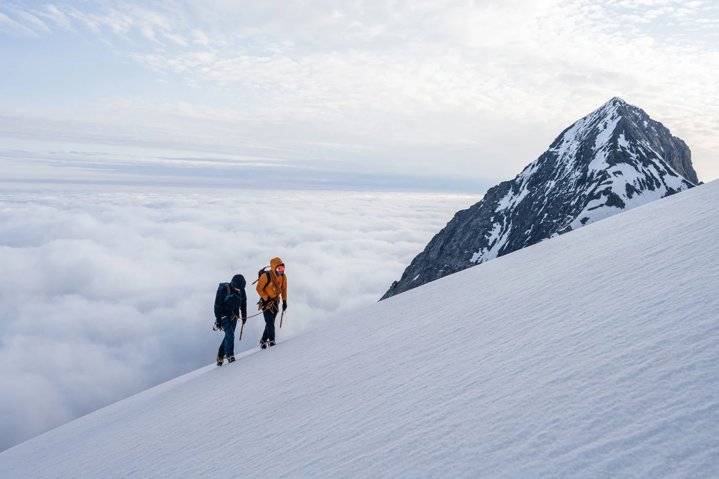 Zwei Hochtourengänge an einem verschneiten Berghang über der Wolkendecke